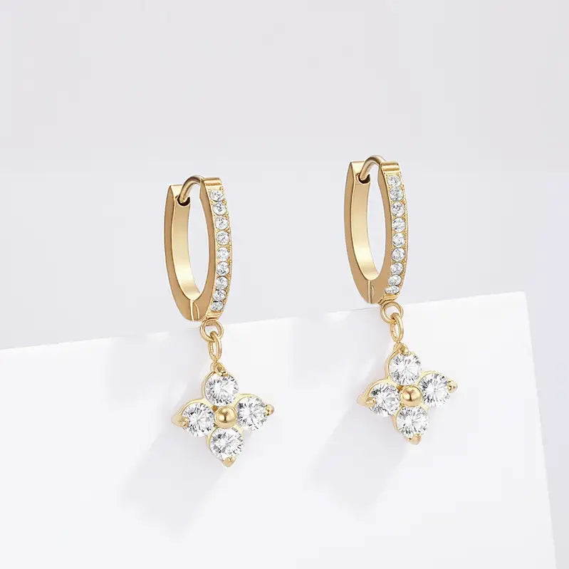 Gold hoop earrings with diamond-like stones on a white background