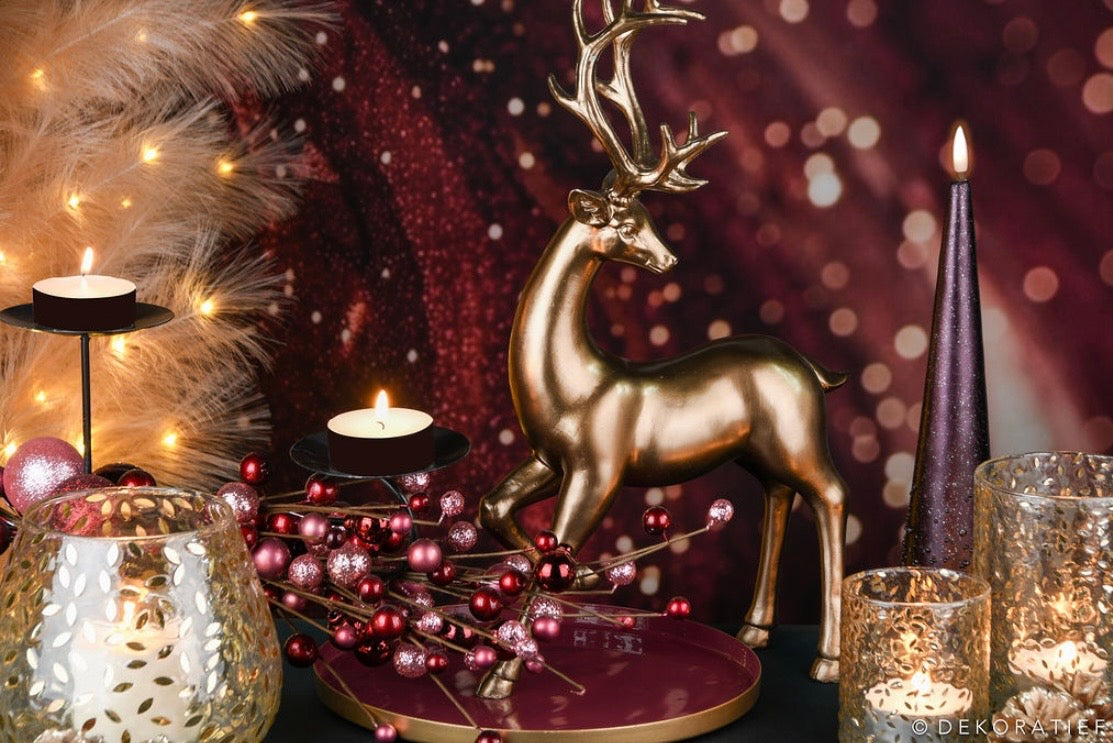 Decorative setup with a gold deer figurine, candles, and festive lights on a dark background.