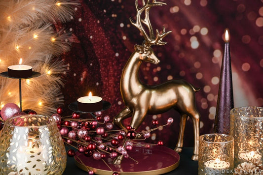 Decorative setup with a gold deer figurine, candles, and festive lights on a dark background.