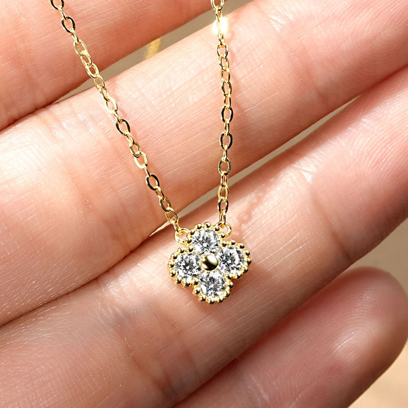 Gold necklace with a diamond pendant held between fingers