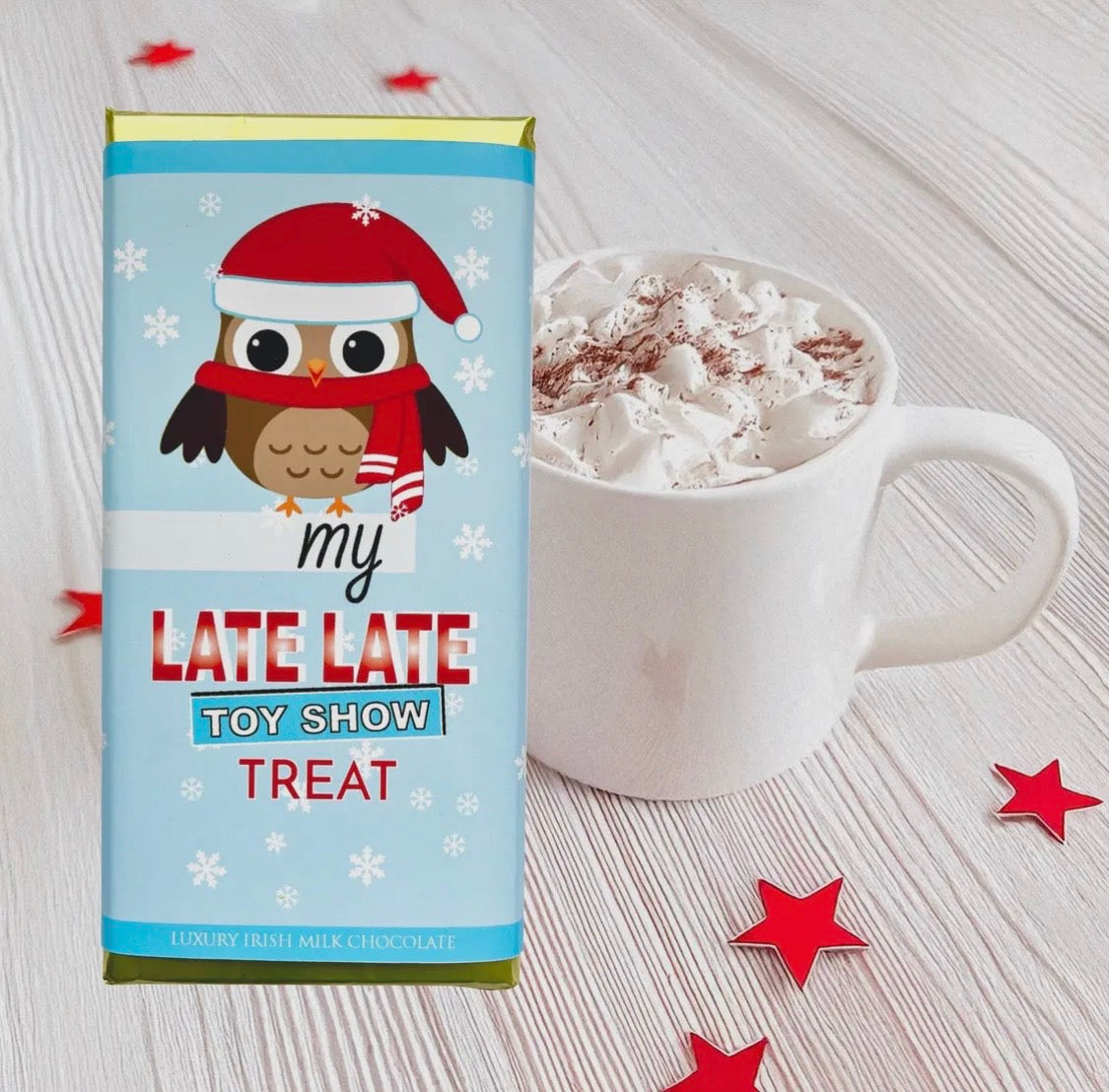 Owl-themed chocolate bar packaging for 'My Late Late Toy Show' next to a mug of hot chocolate.