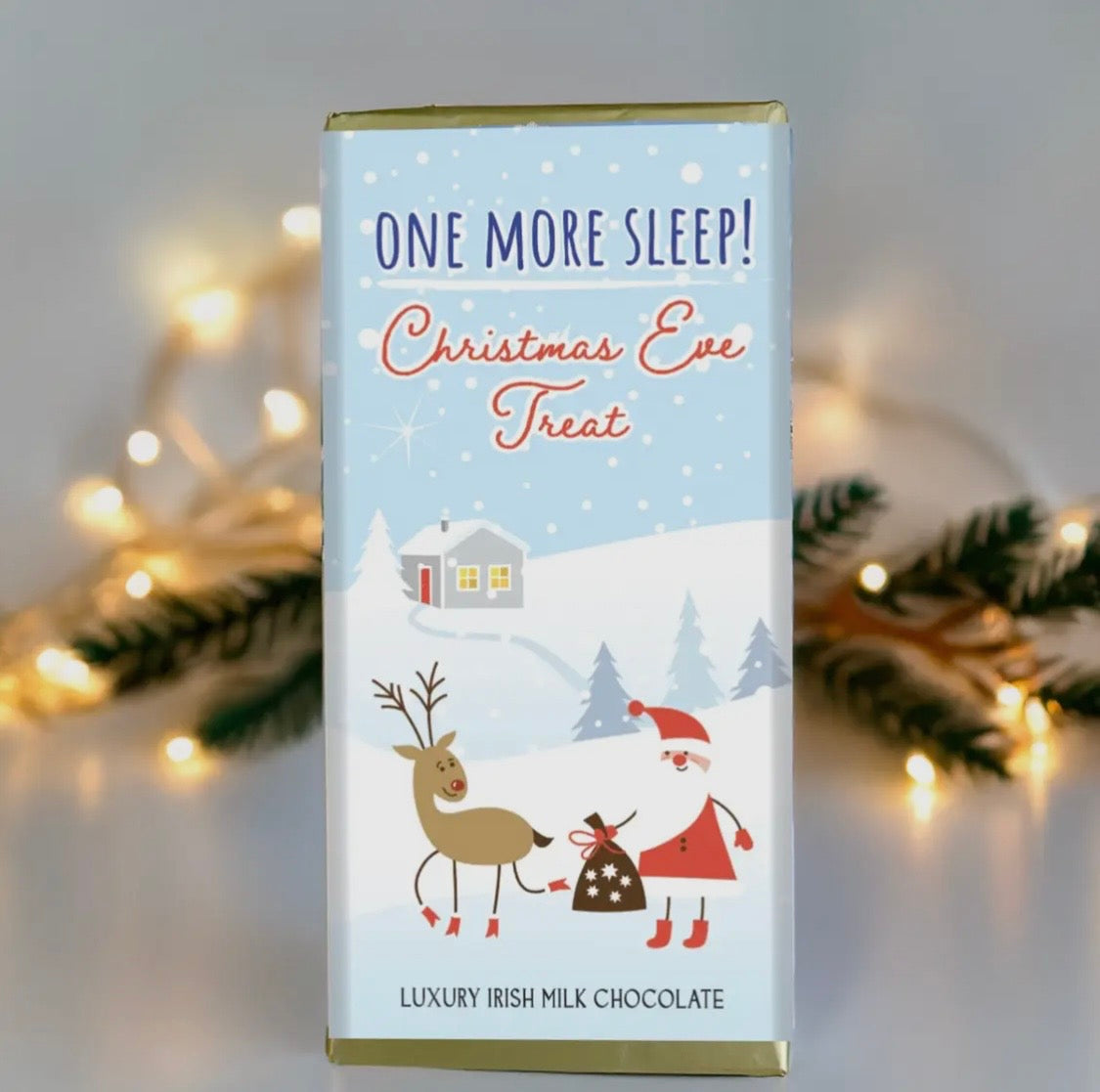 Chocolate bar packaging with Christmas-themed illustration of Santa and reindeer, surrounded by festive lights and decorations.