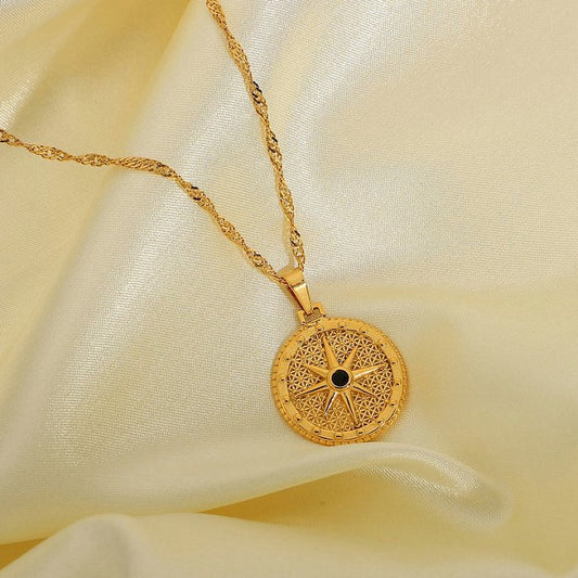 Gold necklace with a intricate pendant on a beige fabric background